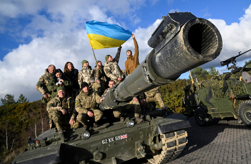  Ukrainian personnel pose with a flag on top of a Challenger 2 tank during a training at Bovington Camp, near Wool in southwestern Britain, February 22, 2023. (photo credit: TOBY MELVILLE/REUTERS)
