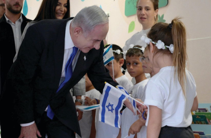  PRIME MINISTER Benjamin Netanyahu bends down to make eye contact with first graders in Ma’aleh Adumim.  (photo credit: Avi Hayoun/GPO)