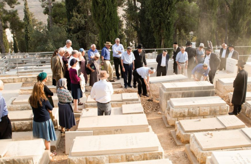  FAMILY MEMBERS cover the remains with the soil of Jerusalem. (photo credit: Olivestone family)