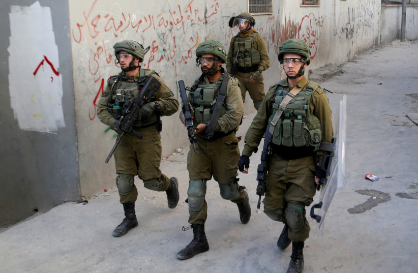 Israeli soldiers walk in the Palestinian al-Arroub refugee camp, in the West Bank November 12, 2019. (photo credit: MUSSA QAWASMA/REUTERS)
