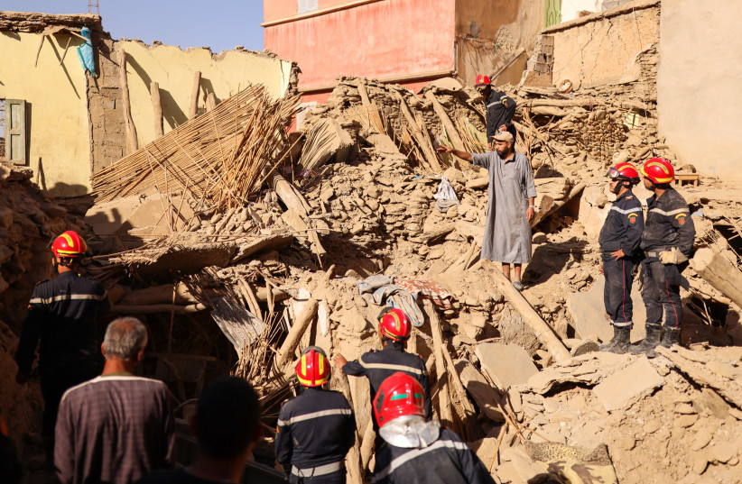  A man gestures next to emergency workers on the rubble, in the aftermath of a deadly earthquake, in Amizmiz, Morocco, September 10, 2023.  (photo credit: NACHO DOCE/REUTERS)