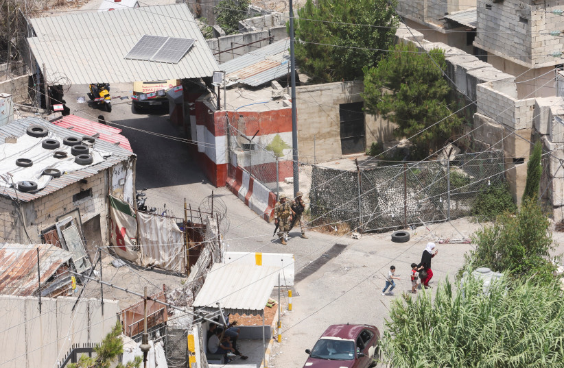  A woman and two children walk near the entrance of the Ain el-Hilweh Palestinian refugee camp during Palestinian faction clashes, in Sidon, Lebanon July 31, 2023. (photo credit: REUTERS/AZIZ TAHER)