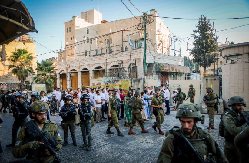  Israeli security forces guard as Jews tour in the West Bank city of Hebron, August 26, 2023 (photo credit: WISAM HASHLAMOUN/FLASH90)