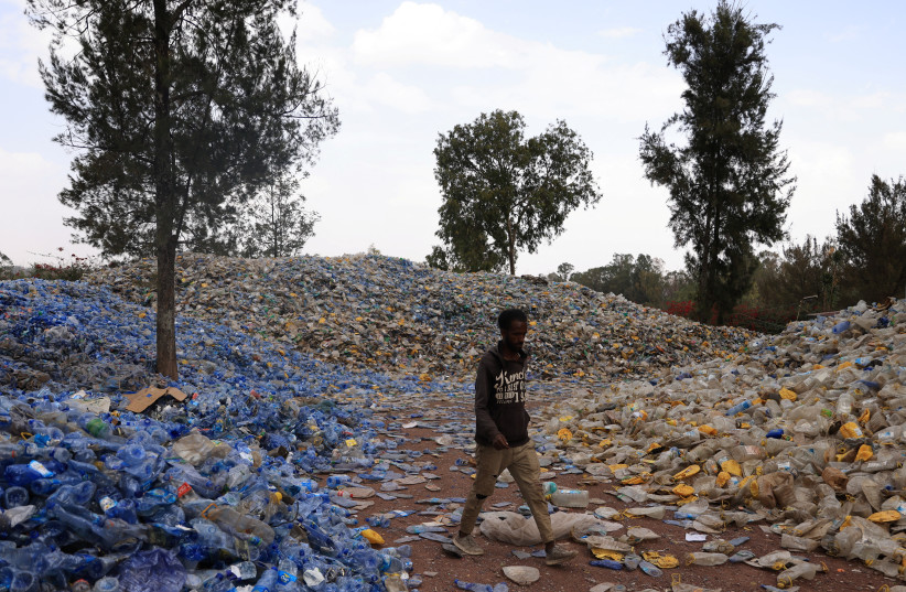  A labourer walks in a sorted piles of recyclable plastic bottles in Addis Ababa, Ethiopia June 2, 2022 (photo credit: REUTERS/TIKSA NEGERI)
