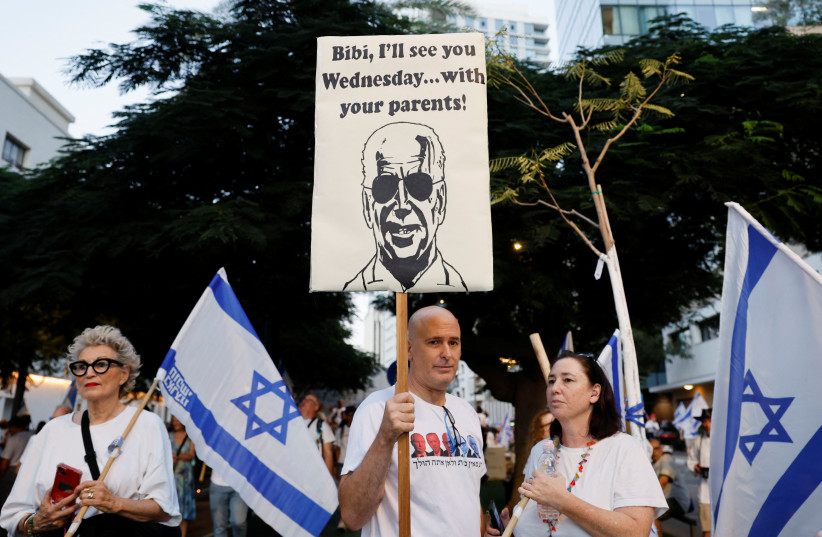  A person holding a placard during a protest as the new Jewish New Year begins in a protest against Prime Minister Benjamin Netanyahu and his nationalist coalition government's judicial reform, in Tel Aviv, Israel, September 17, 2023 (photo credit: REUTERS/AMIR COHEN)