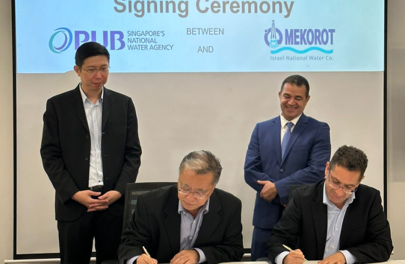  Mekorot vice-president of engineering Yossi Yaakobi signs MOU with PUB assistant CEO, as Mekorot CEO Amit Lang (standing at right) looks on. (photo credit: MEKOROT)