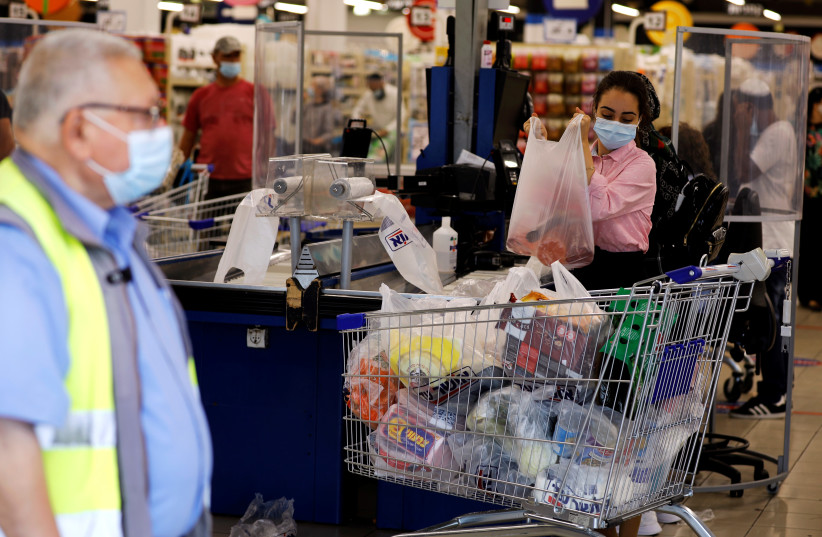 Женщина раскладывает товары на кассе супермаркета в преддверии еврейского Нового года и предстоящего ужесточения ограничений для предотвращения распространения коронавирусной болезни (COVID-19) в Ашдоде, Израиль, 16 сентября 2020 года. (Фото: REUTERS) /АМИР КОЭН)