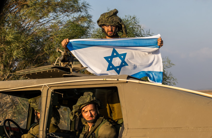 AN IDF soldier on patrol near the Gazan border displays the Israeli flag, this week. This is no longer about containment, but about achieving a definitive victory and the removal of Hamas, says the writer (photo credit: CHAIM GOLDBEG/FLASH90)