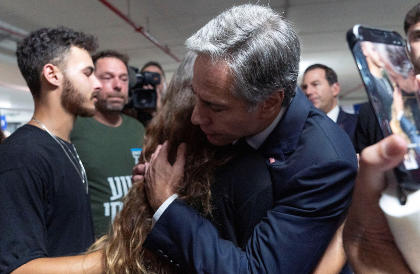 US Secretary of State Antony Blinken is embraced by Lior Gelbaum, right, 24, a dual U.S.-Israeli citizen, and her boyfriend Klil Valiano, as he visits a donation center for victims of the Hamas attacks from Gaza, in Tel Aviv, Israel October 12, 2023 (photo credit: JACQUELYN MARTIN/POOL/REUTERS)