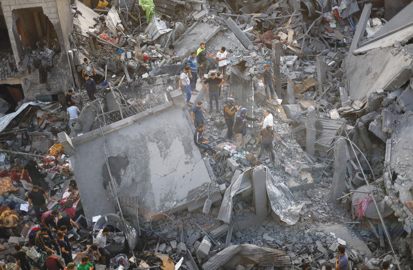  PALESTINIANS INSPECT the damage of an IAF strike at the Magazi refugee camp, in central Gaza (photo credit: MOHAMMED SALEM/REUTERS)