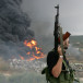 A Lebanese Hezbollah guerrilla looks at a fire rising from a burning object in a Beirut suburb, Lebanon July 17, 2006.