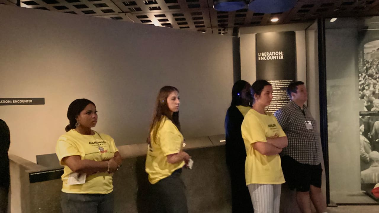 Two Museums Program participants listening at a museum exhibit.