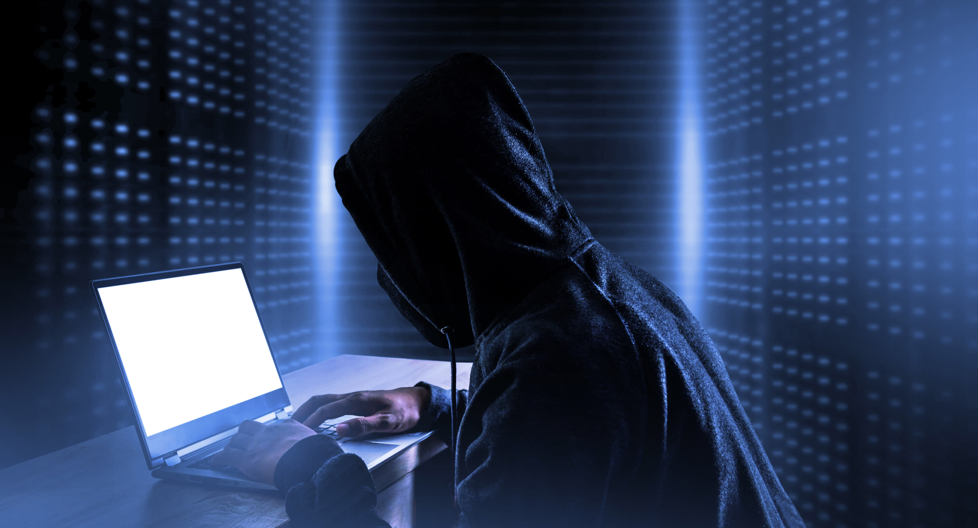 An illustrative image of a person at a computer surrounded by code, indicating hacking or cyberattacks.