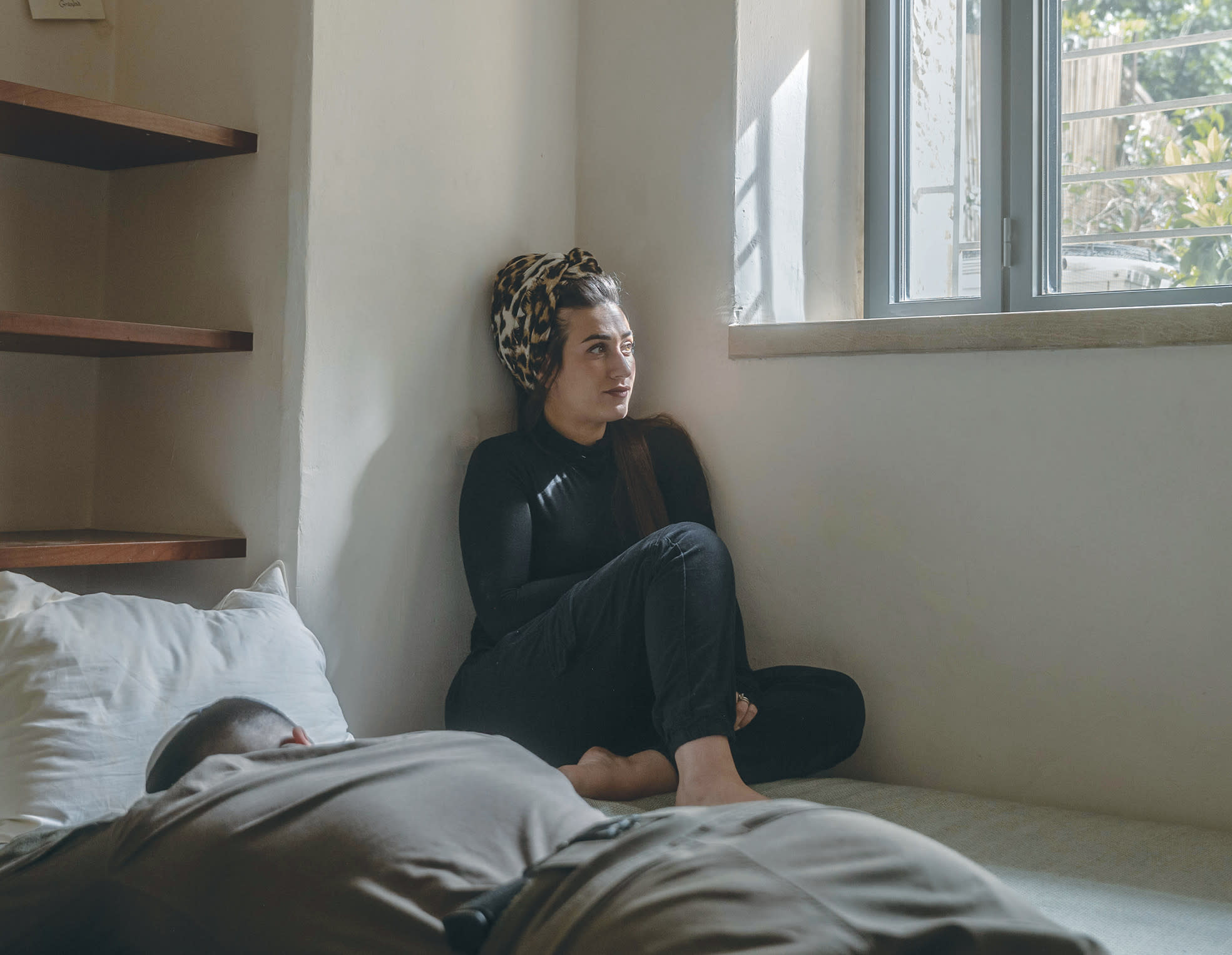 IN THE stillness of the afternoon, Eliana sits alone as her husband sleeps between deployments – a brief pause in a life shaped by long absences, quiet resilience, and the strain of holding everything together.