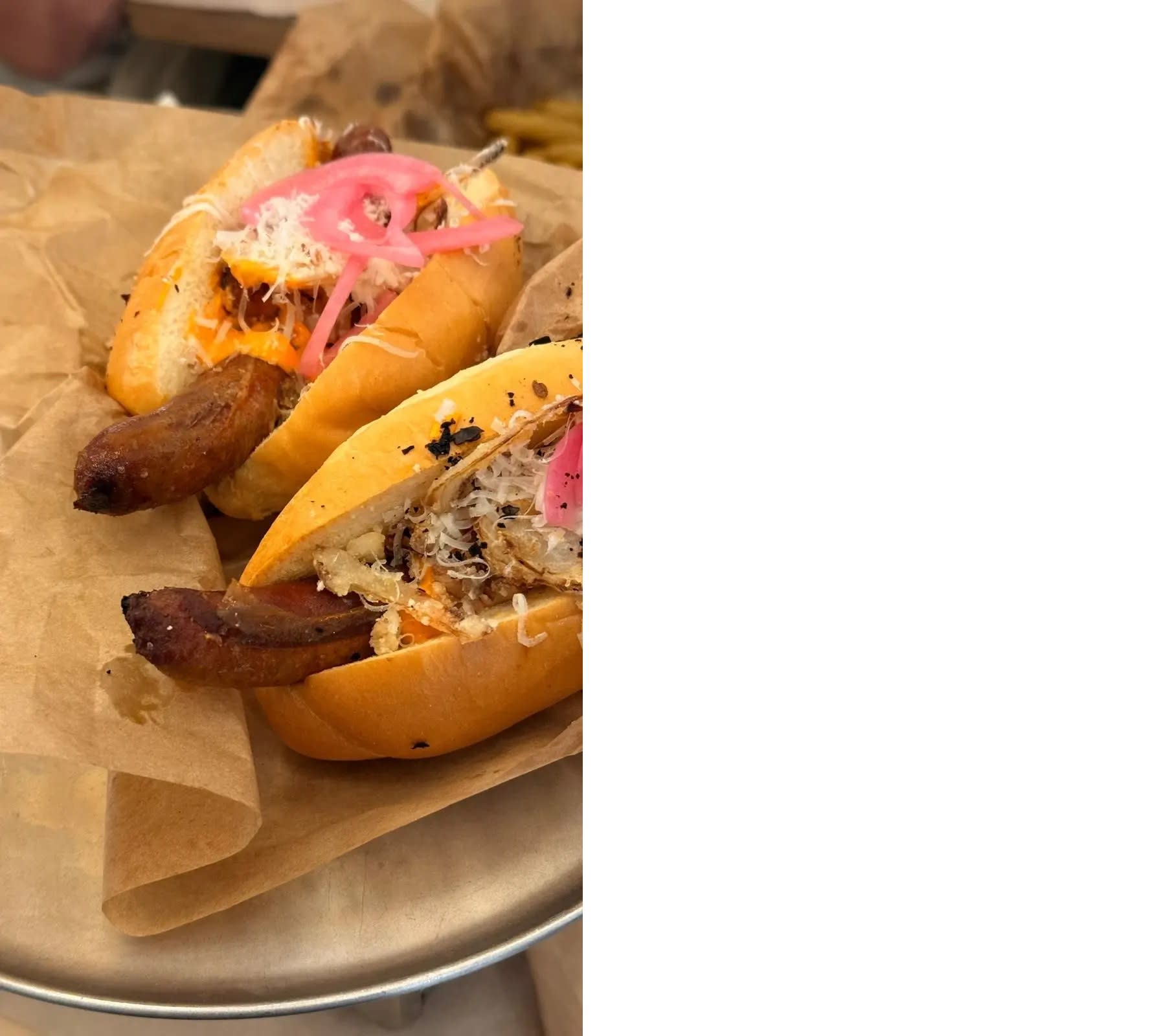 A sausage inside an airy brioche bun with pickled onion