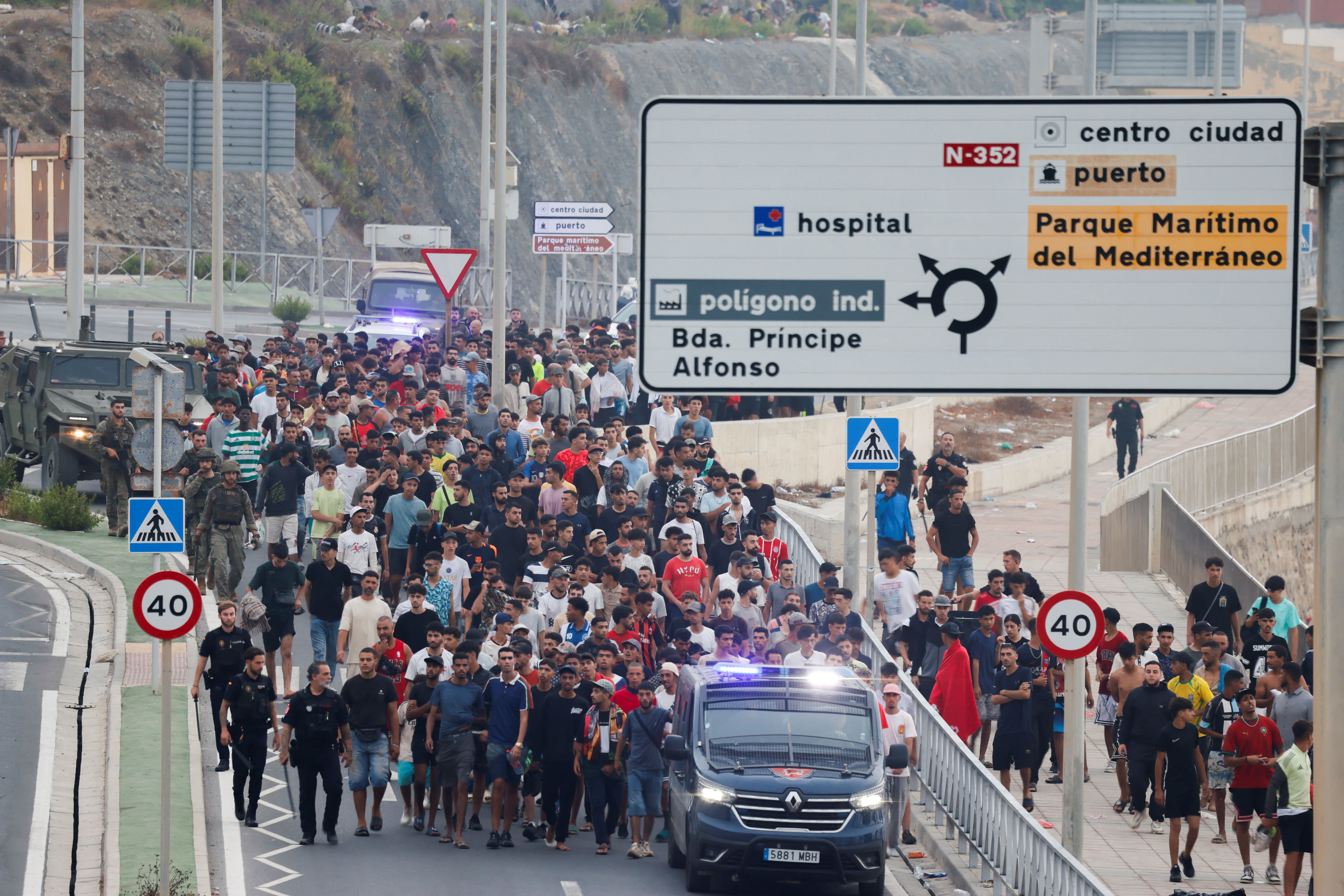 Police officers and Spanish soldiers escort a big group of migrants to the border to take them out of Spain, after mass crossings of migrants on foot and by sea from Morocco into Spanish territory, in Ceuta, Spain, August 1, 2026.