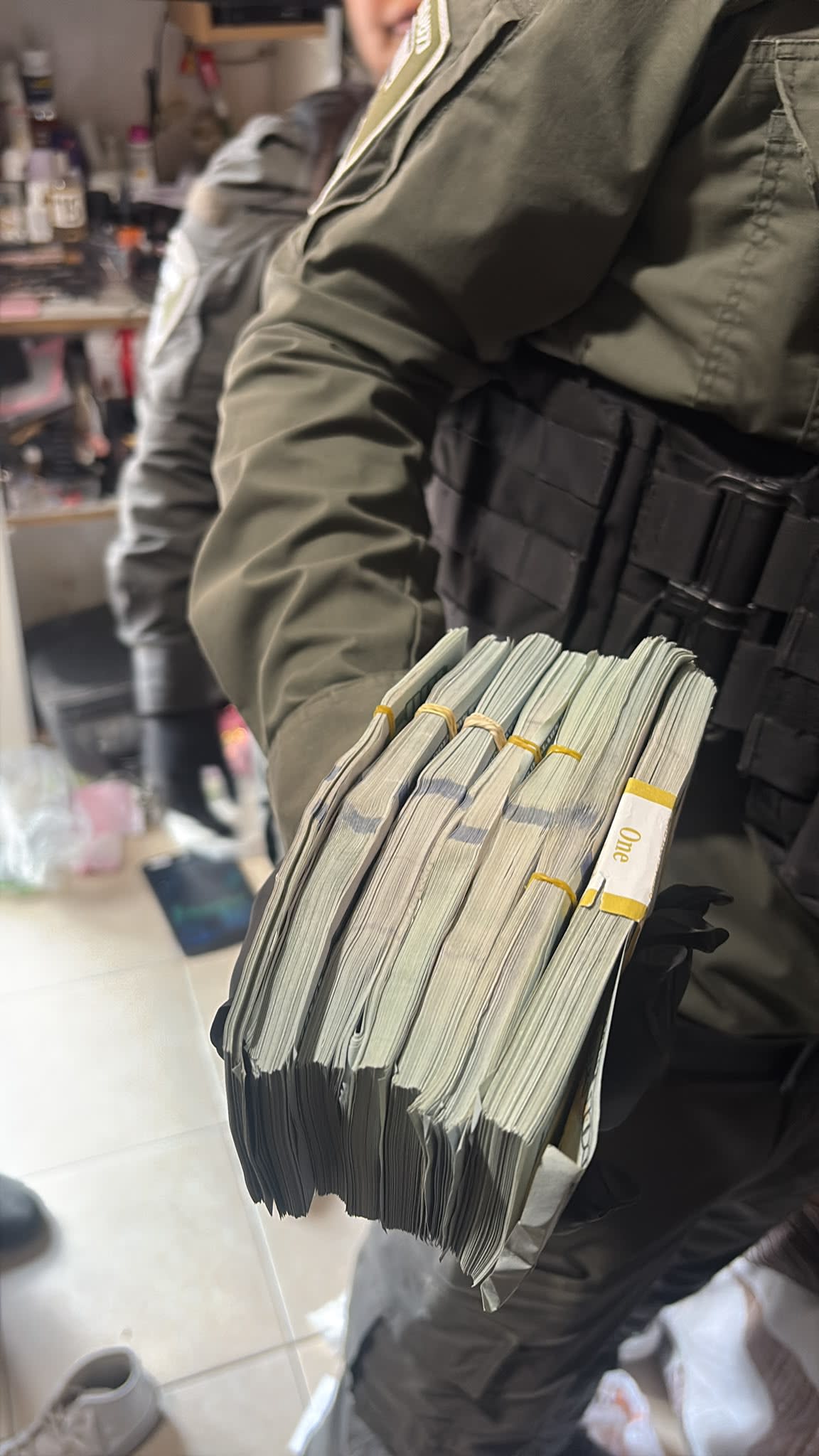 Tel Aviv police officer seen holding cash seized during raids on August 11, 2026.