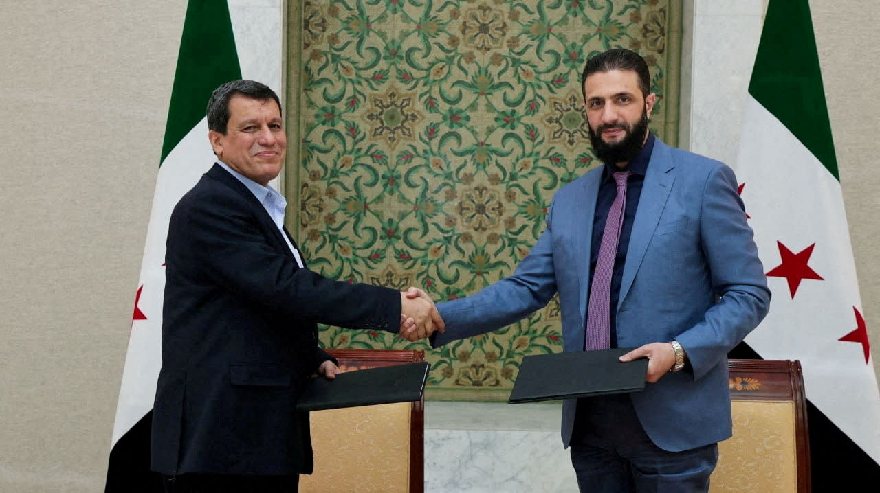 Syrian President Ahmed al-Sharaa and Commander of Syrian Kurdish-led forces Mazloum Abdi shake hands, after Syria reached a deal to integrate the Kurdish-led Syrian Democratic Forces (SDF) with state institutions, in Damascus, Syria, in this handout released on March 10, 2025.