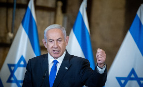 Israeli Prime Minister Benjamin Netanyahu, standing in front of Israeli flags, leads the weekly government conference, held at the Western Wall tunnels in Jerusalem's Old City on May 21, 2023.