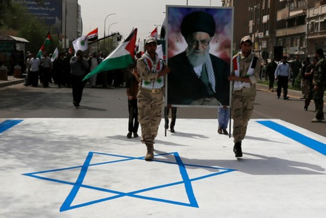 Iraqi muslims from Shi'ite Badr organization hold a portrait of Ayatollah Ali Khamenei as they walk over the Israeli flag during a parade marking Jerusalem Day. (credit: REUTERS)