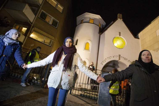 Muslim women join hands to form a human shield as they stand outside a synagogue in Oslo February 21, 2015. More than 1000 Muslims formed a human shield around Oslo's synagogue on Saturday. (credit: REUTERS)