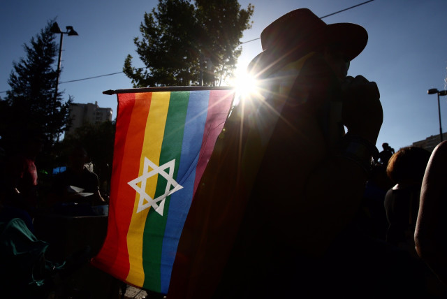 Man holds a Star of David rainbow flag at the 2017 Jerusalem Gay Pride Parade (credit: MARC ISRAEL SELLEM)