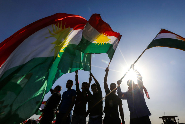 Iraqi Kurds wave flags of Iraqi Kurdistan during a demonstration (credit: SAFIN HAMED / AFP)