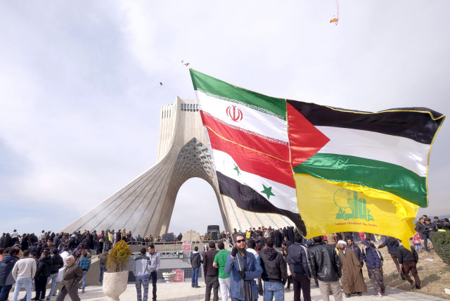 A man carries a giant flag made of flags of Iran, Palestine, Syria and Hezbollah, during a ceremony marking the 37th anniversary of the Islamic Revolution, in Tehran, Feburary 2016 (credit: RAHEB HOMAVANDI/REUTERS)
