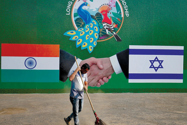 A municipal worker cleans the street in front of a bilboard displaying Indian and Israeli flags for PM Netanyahu's visit, Ahmedabad, India, January 2018 (credit: REUTERS/AMIT DAVE)