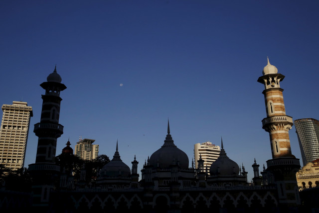 A mosque is silhouetted against city buildings in Kuala Lumpur, Malaysia, January 27, 2016. (credit: OLIVIA HARRIS/ REUTERS)