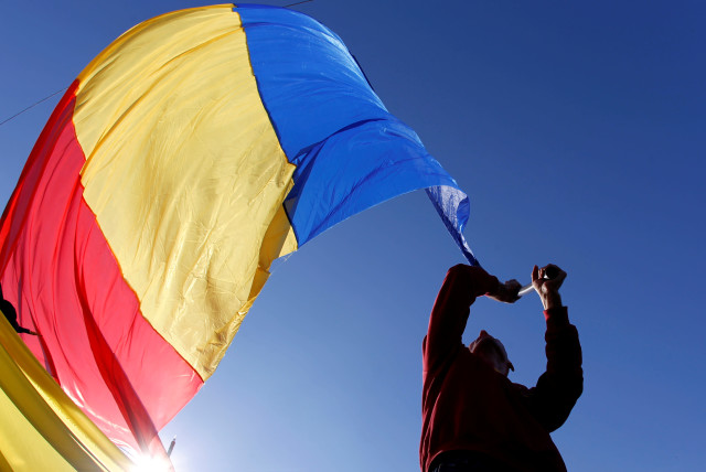 A man waves a Romanian national flag during a march in downtown Bucharest, Romania, October 20, 2013. (credit: REUTERS/BOGDAN CRISTEL)
