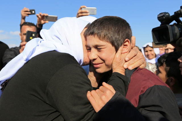 A relative kisses a Yazidi survivor boy following his release from Islamic State militants in Syria, in Duhok, Iraq, March 2, 2019. (credit: ARI JALAL / REUTERS)