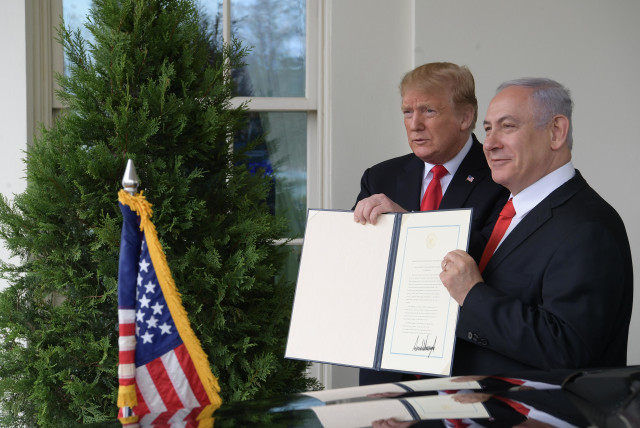 Prime Minister Benjamin Netanyahu and US President Donald Trump hold up the signed document acknowledging Israeli sovereignty over the Golan Heights, on March 25, 2019 (credit: AMOS BEN-GERSHOM/GPO)