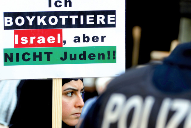 A protester holds a placard reading ‘I boycott Israel, but not the Jews,’ during a demonstration marking al-Quds Day (Jerusalem Day), in Berlin on June 1 (credit: FABRIZIO BENSCH / REUTERS)