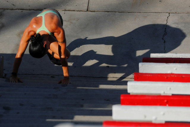 A woman does her morning workout along the beach in Oceanside (credit: REUTERS)