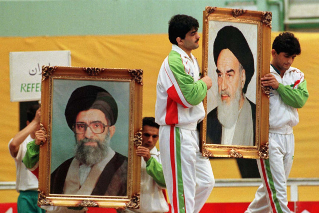 Iranian wrestlers carry portraits of Iran’s late leader Ayatollah Ruhollah Khomeini and today’s leader Ayatollah Ali Khamenei at the opening ceremony of the Takhti Cup tournament in Tehran in 1998 (credit: REUTERS)