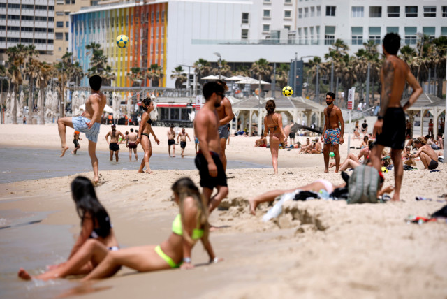 People visit a beach along the coast of the Mediterranean Sea during a heatwave in Israel as restrictions following the coronavirus disease (COVID-19) ease around the country, in Tel Aviv, Israel, May 17, 2020 (credit: REUTERS/AMIR COHEN)