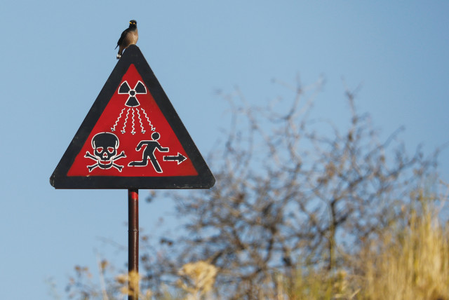 A BIRD SITS on a radiation sign at the uranium ore dump near the town of Mailuu-Suu, Kyrgyzstan. (credit: PAVEL MIKHEYEV/REUTERS)