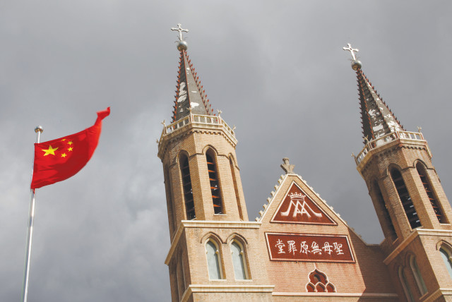 The Chinese flag flies in front of a Catholic church in the village of Huangtugang, China. (credit: THOMAS PETER/REUTERS)