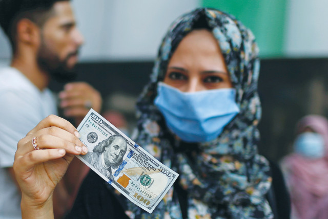 A WOMAN shows a $100 bill she received as aid from Qatar, during a lockdown amid the coronavirus outbreak in Gaza City in September.  (credit: MOHAMMED SALEM/ REUTERS)