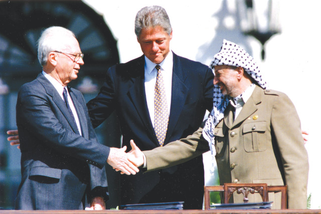 US PRESIDENT Bill Clinton watches prime minister Yitzhak Rabin and PLO chairman Yasser Arafat shake hands after signing the Oslo I Accord, at the White House in Washington on September 13, 1993. (photo credit: GARY HERSHORN/REUTERS)