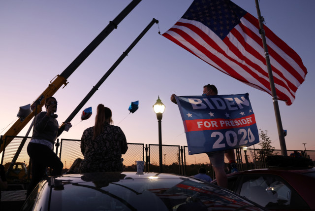 Supporters of Democratic US presidential nominee Joe Biden dance just outside the security perimeter of a planned election celebration as they await his remarks and fireworks in Wilmington, Delaware, US November 7, 2020. (credit: JONATHAN ERNST / REUTERS)