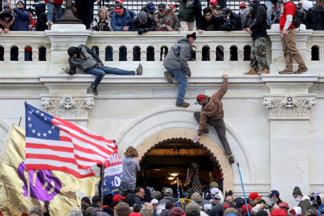 A mob of supporters of former US President Donald Trump fight with members of law enforcement at a door they broke open as they storm the US Capitol Building in Washington, US, January 6, 2021. (credit: REUTERS/LEAH MILLIS/FILE PHOTO)