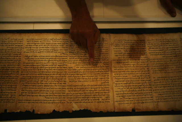 Adolfo Roitman, curator of the Dead Sea Scrolls, points at the original Isaiah Scroll, one of the Dead Sea Scrolls, inside a secured climate-controlled room in the Shrine of the Book at the Israel Museum in Jerusalem September 26, 2011. (credit: BAZ RATNER/REUTERS)