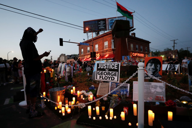 A person raises his fist at a memorial during a Celebration of Life festival in honor of George Floyd, who was killed by Minneapolis police one year ago, at George Floyd Square in south Minneapolis, Minnesota, US, May 25, 2021. (credit: ERIC MILLER/REUTERS)