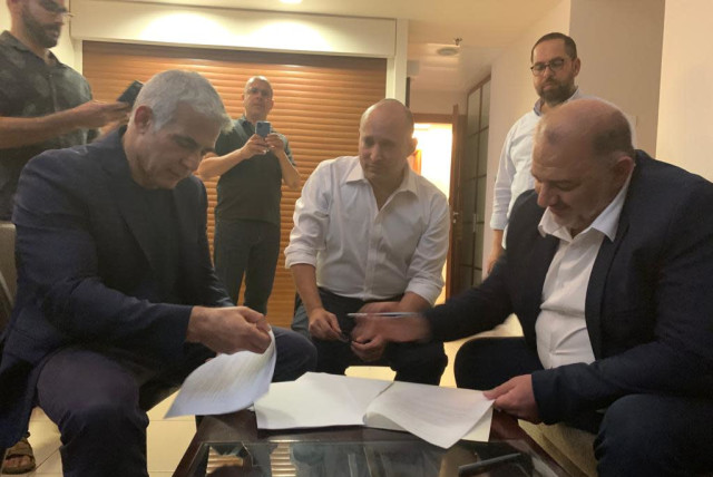 Naftali Bennett, Yair Lapid and Mansour Abbas are seen signing a coalition deal. (credit: RA'AM)