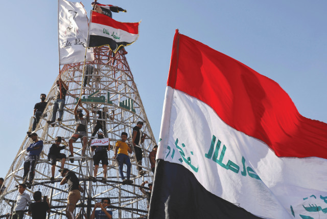DEMONSTRATORS CLIMB a structure during an anti-government protest in Baghdad, 2021. (credit: THAIER AL-SUDANI/REUTERS)