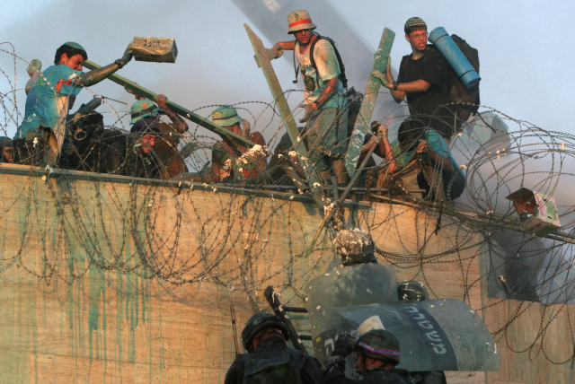  Opponents of Israel's disengagement plan try to prevent Israeli security forces from reaching the rooftop of a synagogue in the Jewish settlement of Kfar Darom, in the Gush Katif settlements bloc, southern Gaza Strip, August 18, 2005. (credit: PAUL HANNA/REUTERS)