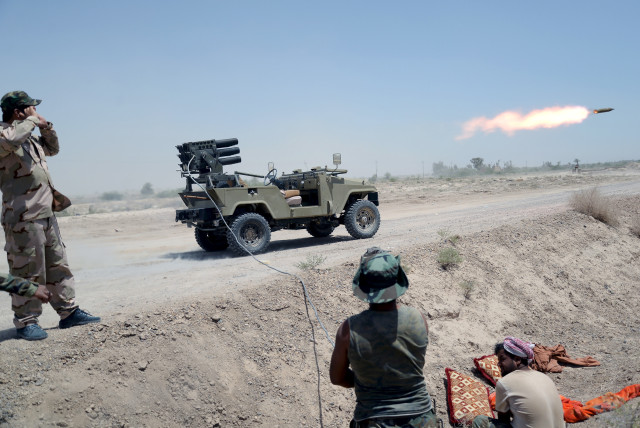  IRAQI SHI’ITE paramilitaries  launch a rocket towards Islamic  State operatives, north of  Fallujah, 2015. (credit: STRINGER/ REUTERS)