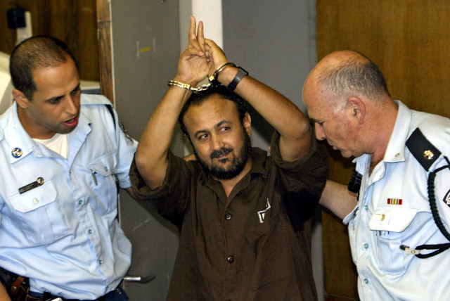  MARWAN BARGHOUTI gestures as  Israel Police bring him into Tel Aviv  District Court for a judgment hearing,  2004.  (credit: DAVID SILVERMAN / REUTERS)